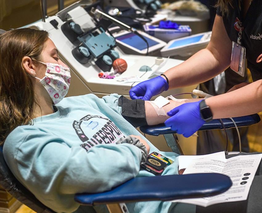 A nurse adjusts the arm of a person donating blood