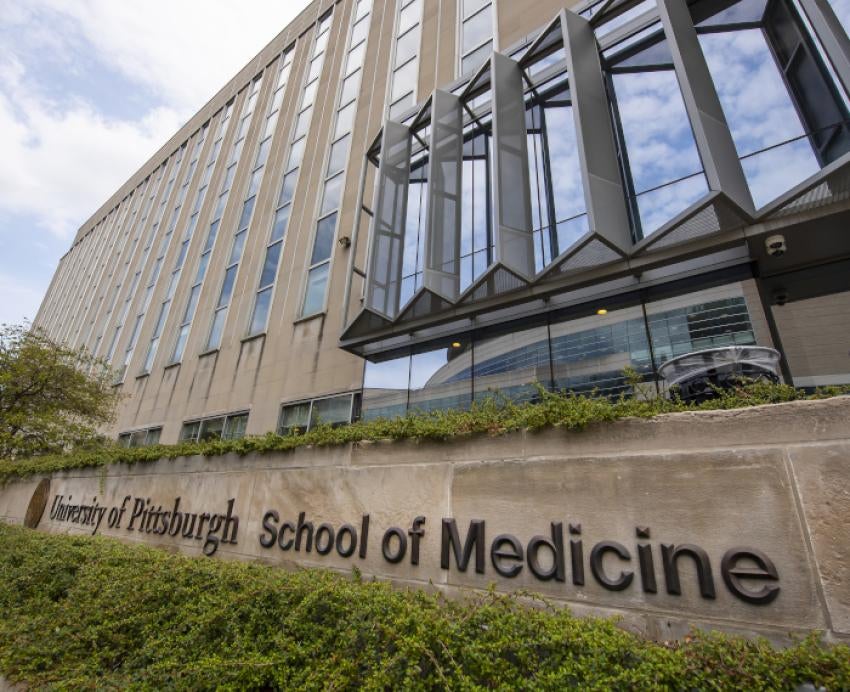 A sign in front of Scaife Hall reading "University of Pittsburgh School of Medicine"