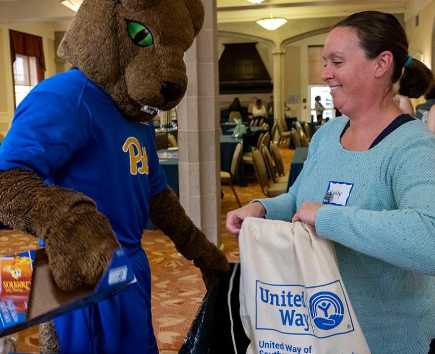 ROC packs cereal into a United Way bag, held by a volunteer