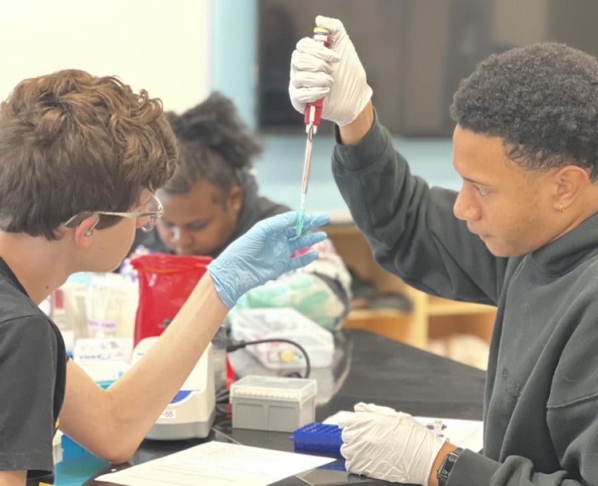 Two students pipette liquid into a vial 