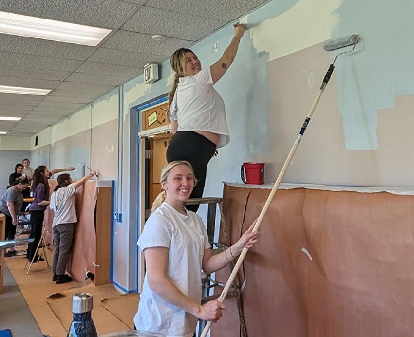 Students paint a wall with rollers