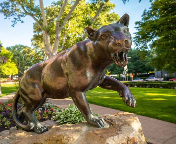 a bronze statue of a panther with its left front paw raised and mouth wide