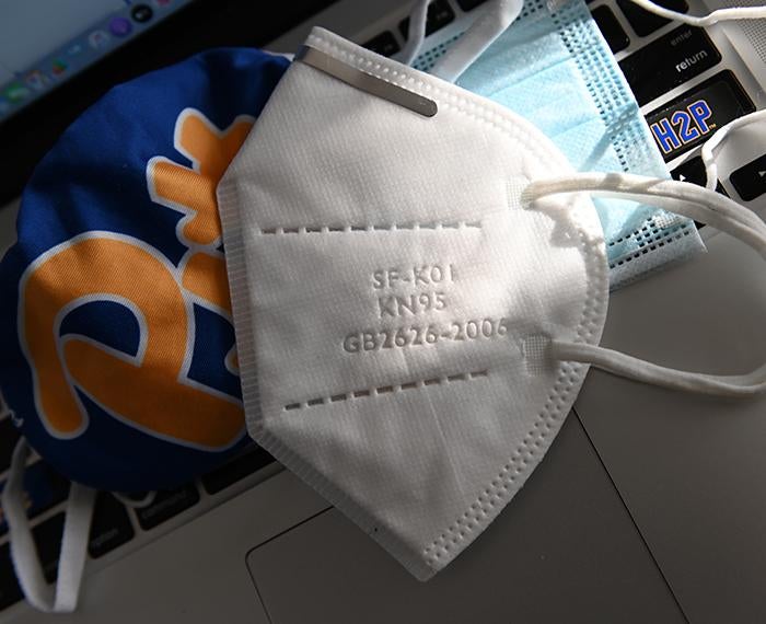 N95 mask laying on computer with Pitt logo