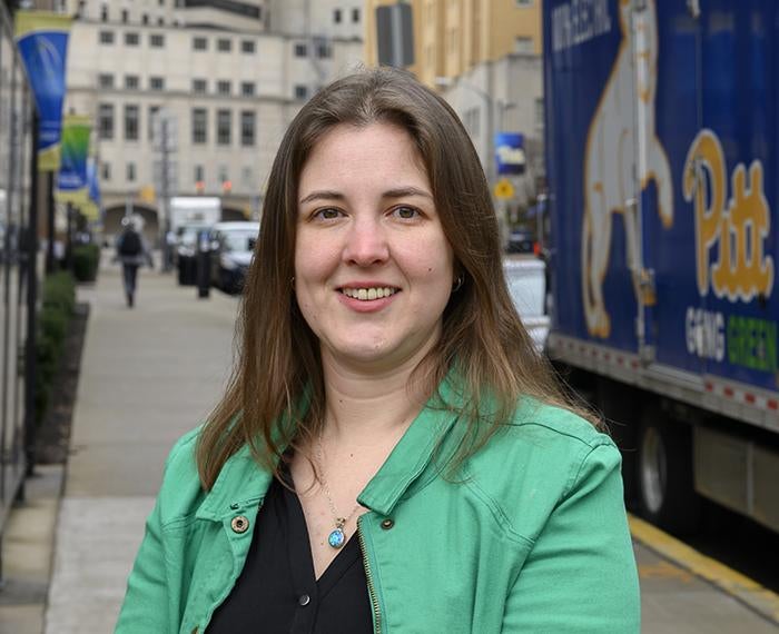 Aurora Sharrard smiling in a green jacket near a Pitt truck