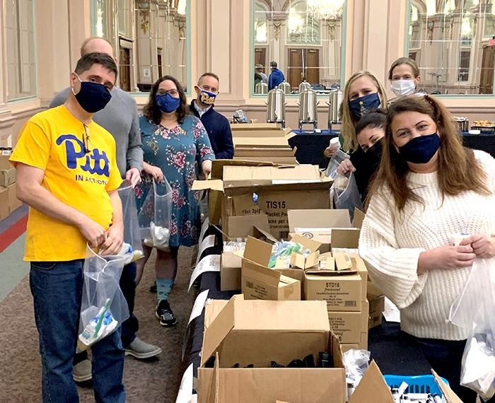 a group of masked volunteers packing boxes