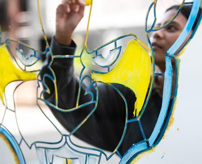 A person is reflected drawing a panther on a mirror
