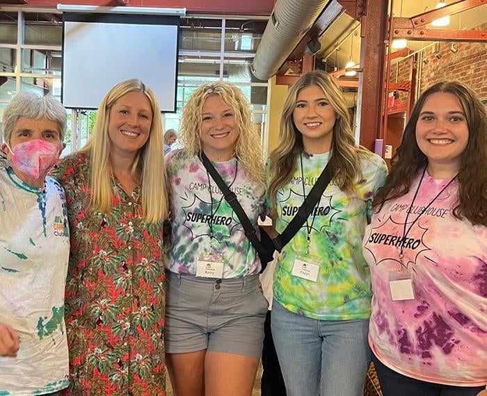 A group of camp counselors stand in tie-dye shirts