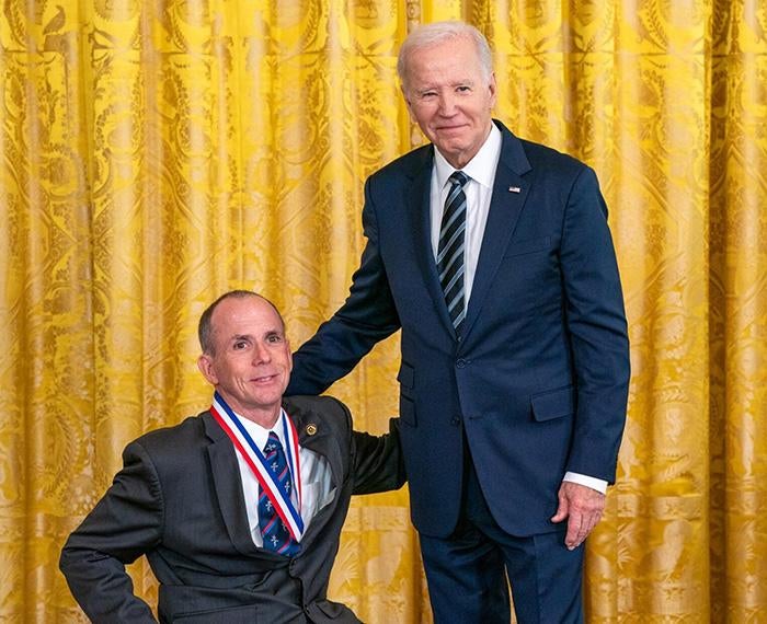 Cooper, wearing a medal, poses with President Biden