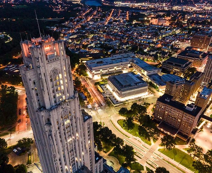 A drone photo of the Cathedral of Learning and Pitt's campus at night