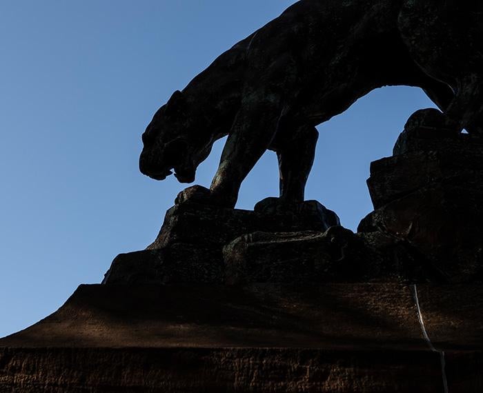 The silhouette of a panther statue against a blue sky