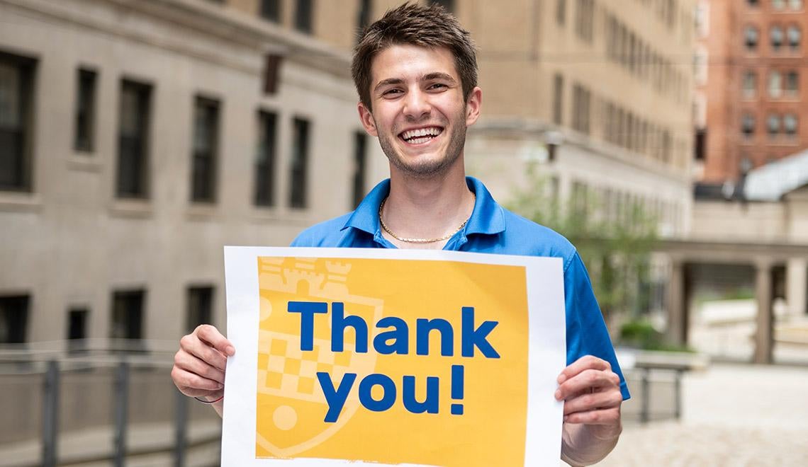 a young man holding a "Thank you!" sign
